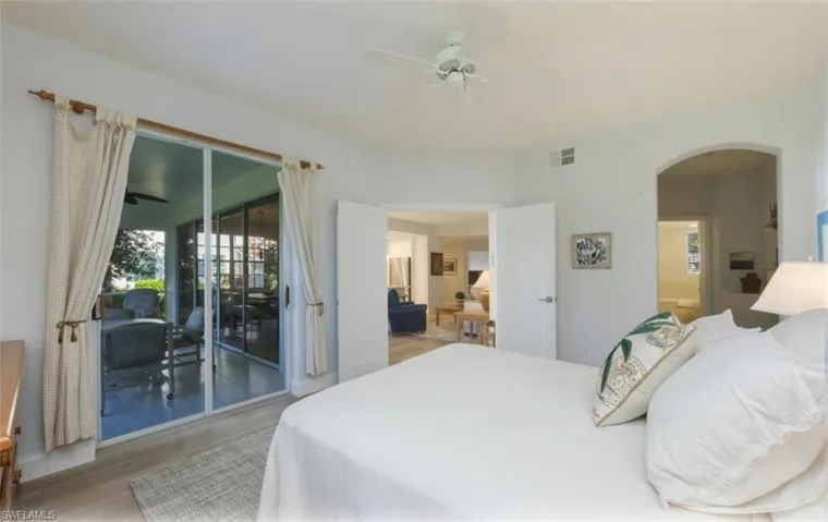 Bedroom with light wood-style floors, arched walkways, a ceiling fan, access to exterior, and ensuite bathroom