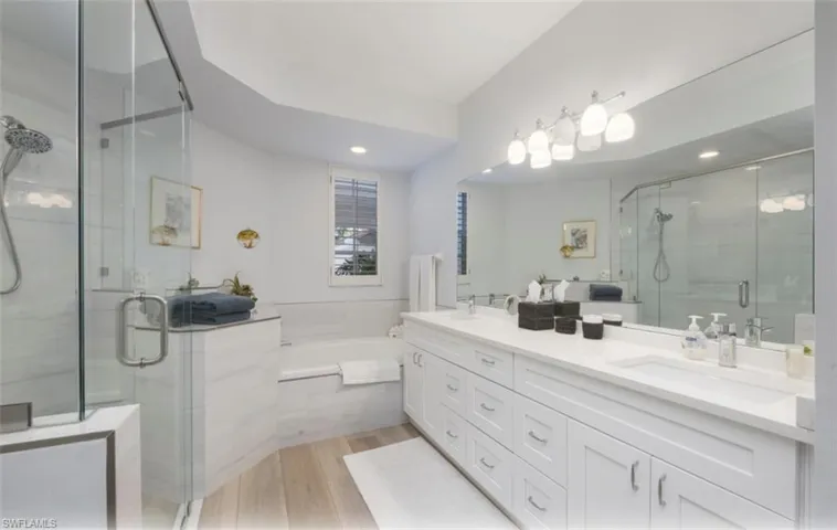 Full bath featuring double vanity, a stall shower, a bath, and light wood finished floors