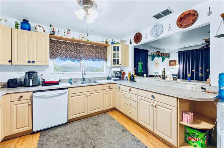 Kitchen featuring light wood-type flooring, kitchen peninsula, sink, and dishwasher