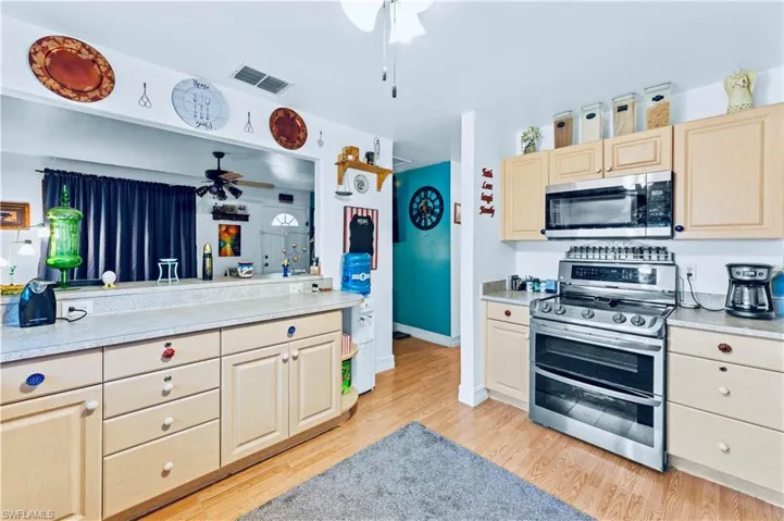 Kitchen with stainless steel appliances, light brown cabinets, ceiling fan, and light hardwood / wood-style flooring
