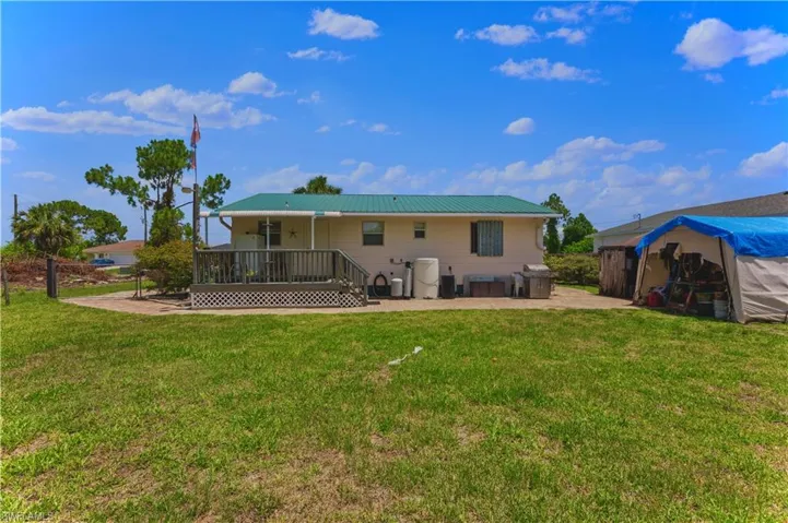 Rear view of property with an outdoor structure and a yard