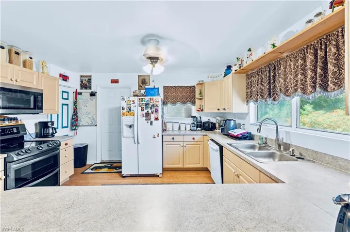 Kitchen featuring light hardwood / wood-style flooring, white appliances, sink, ceiling fan, and light brown cabinets