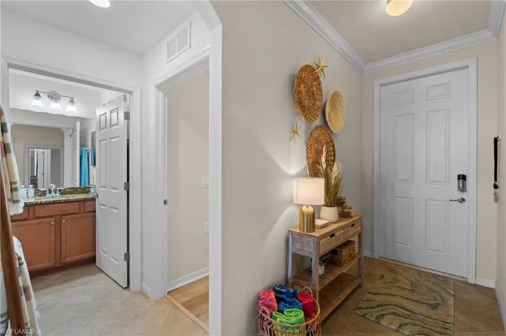 Foyer with baseboards, visible vents, arched walkways, and ornamental molding