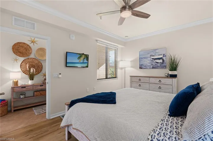 Bedroom featuring light wood finished floors, visible vents, and ornamental molding
