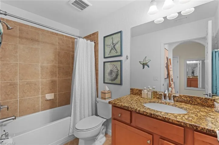 Bathroom with toilet, vanity, visible vents, tile patterned floors, and shower / bath combination with curtain