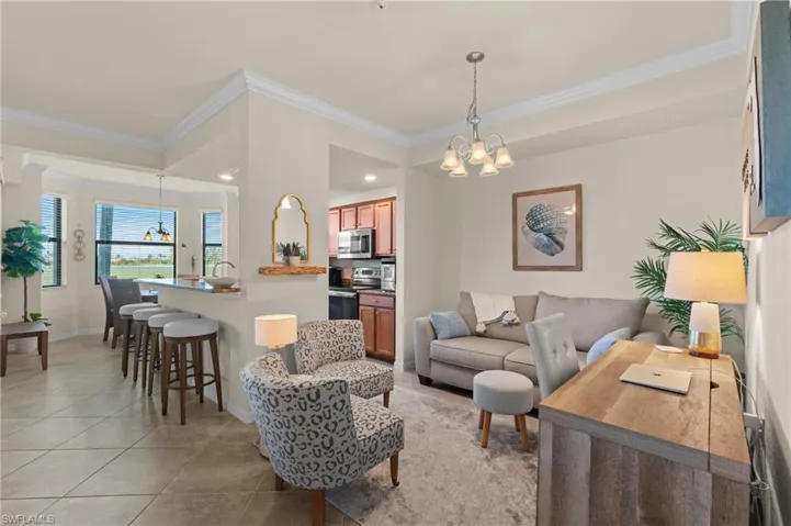 Living room with light tile patterned floors, crown molding, baseboards, and a notable chandelier