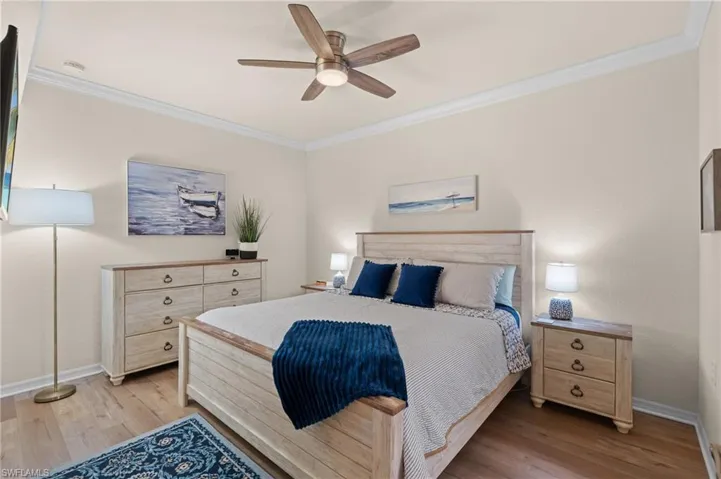 Bedroom with light wood-type flooring, baseboards, and crown molding