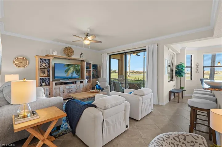 Living room with light tile patterned floors, crown molding, baseboards, and a wealth of natural light