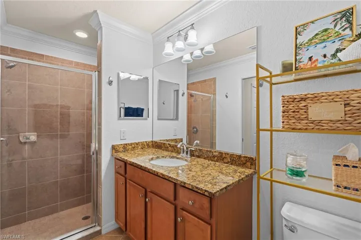 Bathroom featuring toilet, ornamental molding, a shower stall, vanity, and tile patterned flooring