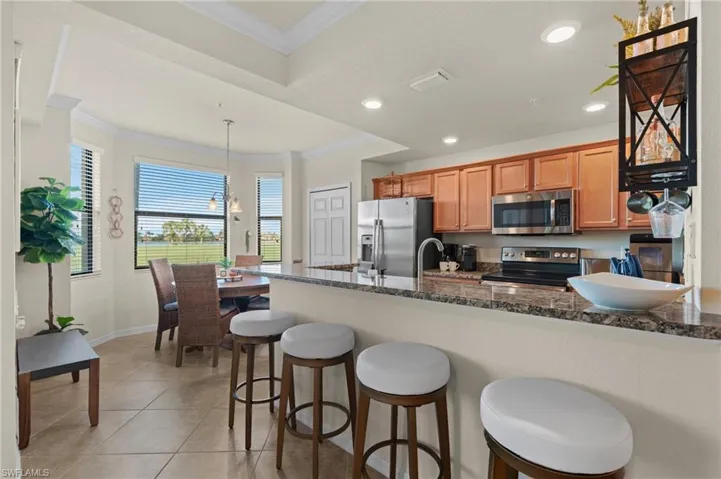 Kitchen featuring pendant lighting, crown molding, visible vents, appliances with stainless steel finishes, and dark stone counters