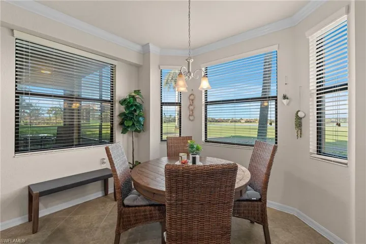 Dining area with ornamental molding, tile patterned flooring, baseboards, and an inviting chandelier