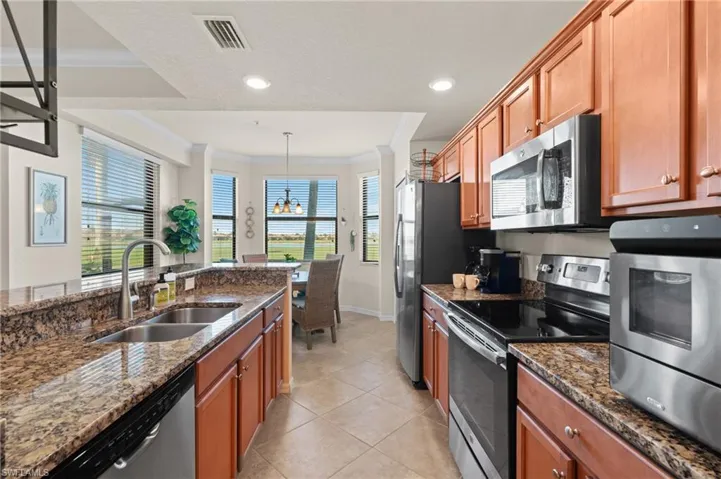 Kitchen featuring a sink, visible vents, appliances with stainless steel finishes, dark stone counters, and pendant lighting