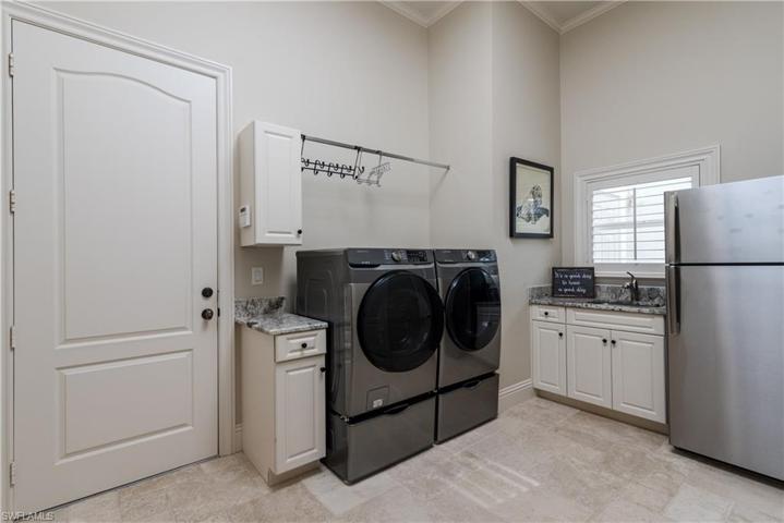 Large Laundry with granite counters, laundry tub, crown molding and walk-in closet
