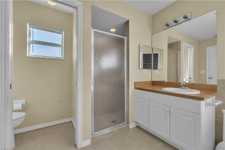 Full bathroom with a stall shower, vanity, and light tile patterned floors