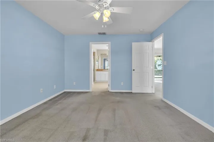 Unfurnished bedroom with a ceiling fan, carpet, and ensuite bath