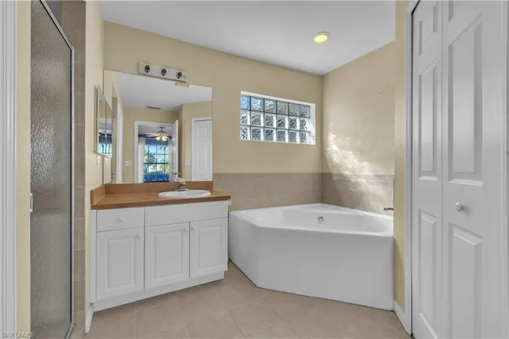 Full bath with vanity, a stall shower, a garden tub, light tile patterned flooring, and a closet