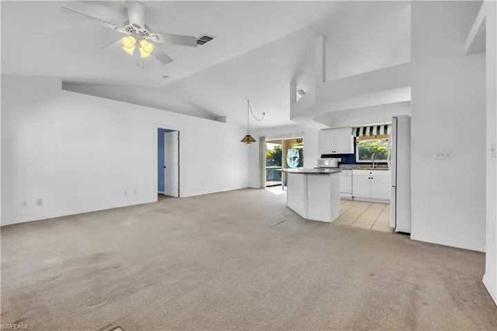 Unfurnished living room featuring light carpet, a ceiling fan, and lofted ceiling