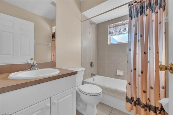 Full bathroom with shower / bath combo with shower curtain, vanity, and light tile patterned floors