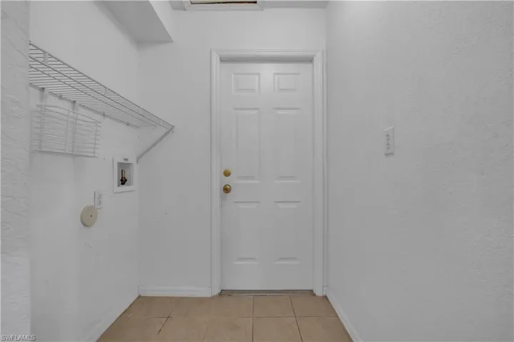 Laundry area featuring a textured wall, light tile patterned flooring, and washer hookup