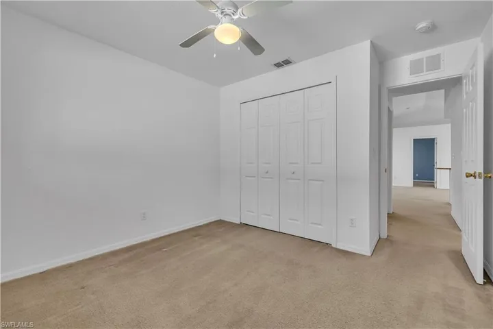 Unfurnished bedroom featuring light carpet, a closet, and a ceiling fan