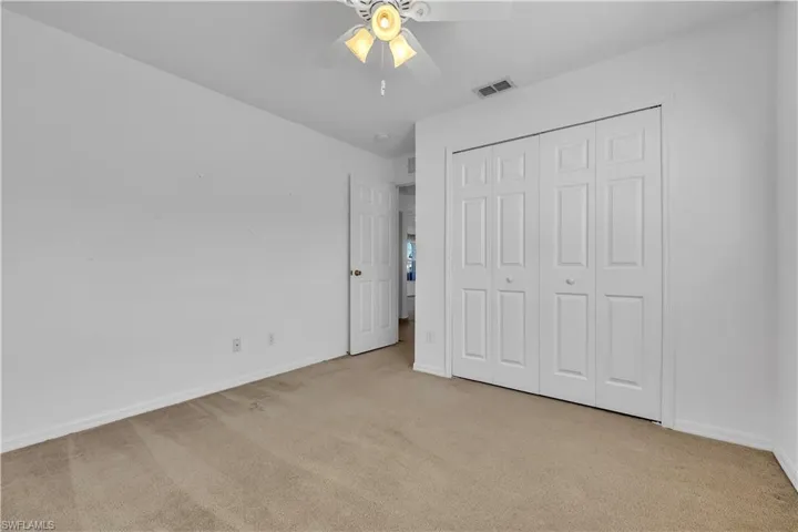 Unfurnished bedroom with light colored carpet, a ceiling fan, and a closet