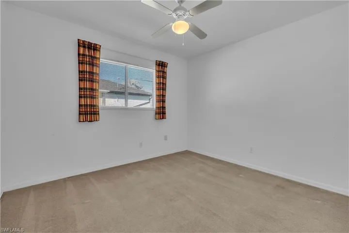 Spare room with light carpet and a ceiling fan