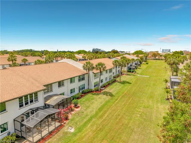 The property features a well-maintained lawn and mature palm trees, with an enclosed patio area for outdoor enjoyment