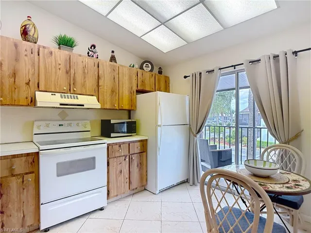 The kitchen features wooden cabinetry, white appliances, and a tiled floor