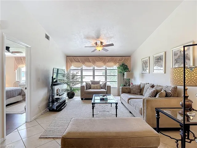 The living area features a ceiling fan, tiled flooring, and a large window with draped valances