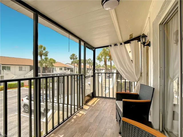 The property features a screened-in balcony with wood-look flooring and a view of palm trees