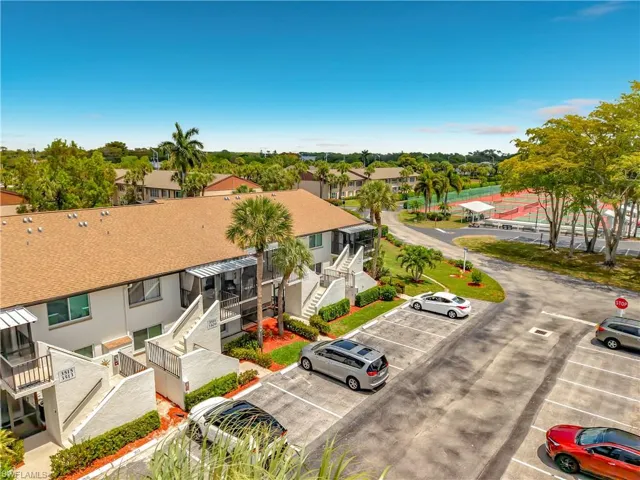 The property features a multi-story building with a brown shingle roof, screened-in balconies, and well-maintained landscaping