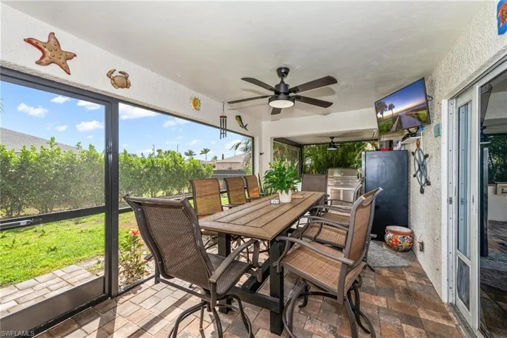Sunroom with outdoor dining area, a ceiling fan, and a patio