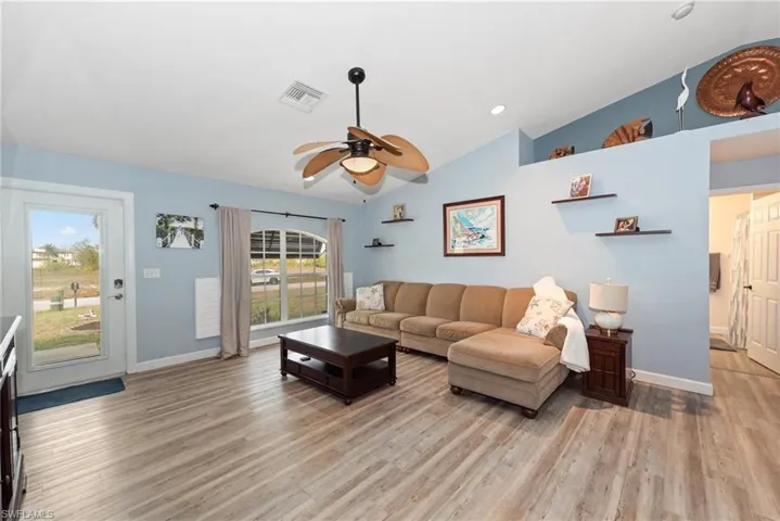 Living room with vaulted ceiling, ceiling fan, light wood finished floors, and recessed lighting
