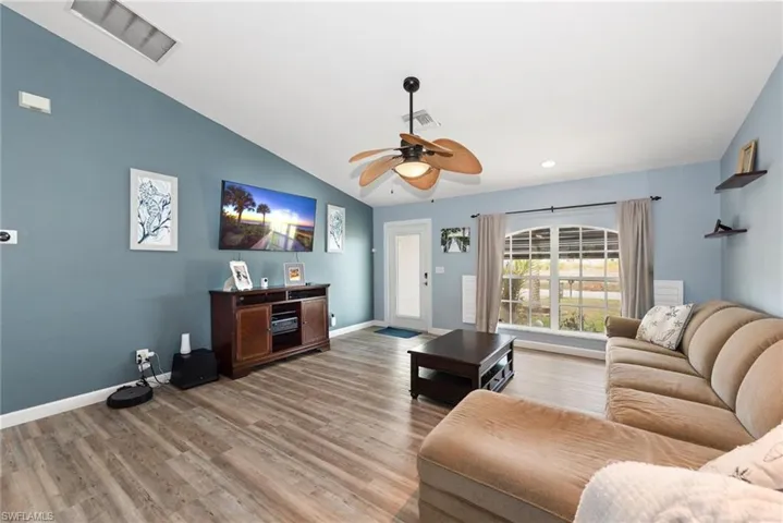 Living room with a ceiling fan, light wood-type flooring, and vaulted ceiling