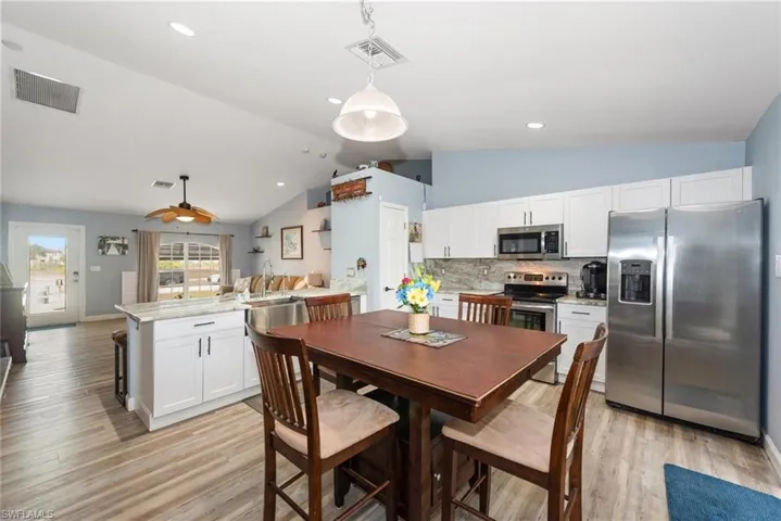 Dining area featuring light wood-style floors, lofted ceiling, and recessed lighting