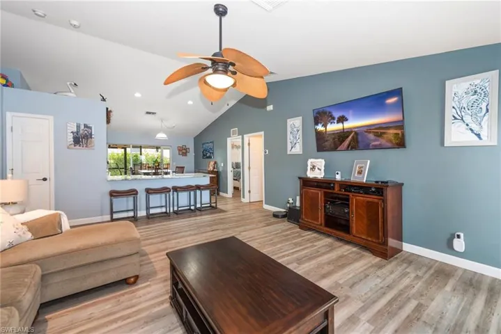 Living room featuring light wood-type flooring, ceiling fan, lofted ceiling, and recessed lighting