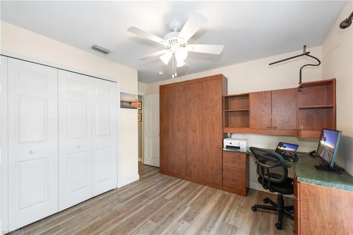 Office area with built in desk, a ceiling fan, and light wood finished floors