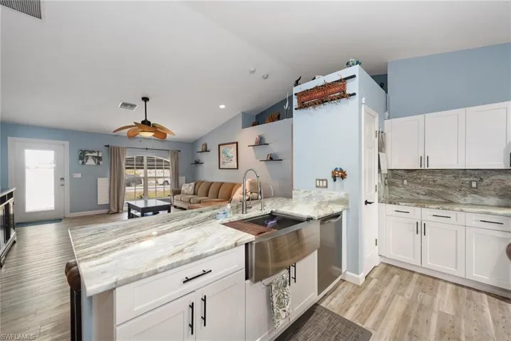 Kitchen featuring white cabinets, a peninsula, light wood-style flooring, open floor plan, and ceiling fan