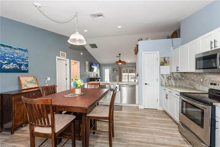 Dining room with lofted ceiling, light wood-style flooring, and recessed lighting