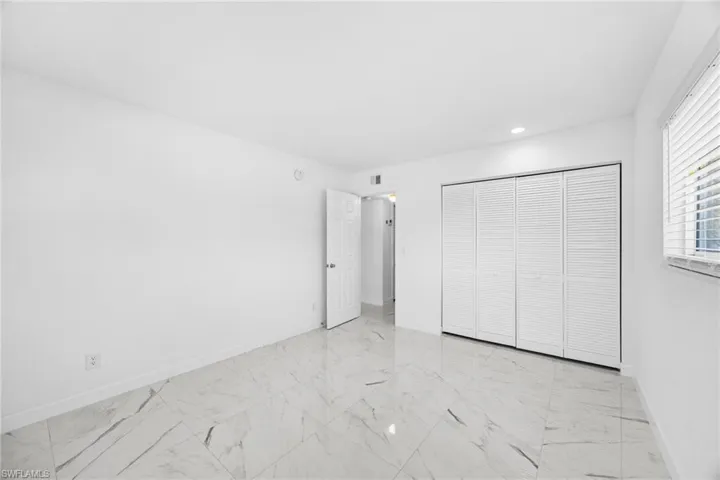 Unfurnished bedroom featuring light marble finish floors, a closet, and recessed lighting