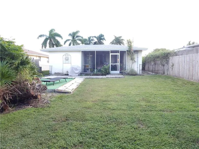 Backyard featuring an expansive lawn, a screen-enclosed patio, and perimeter wood fencing