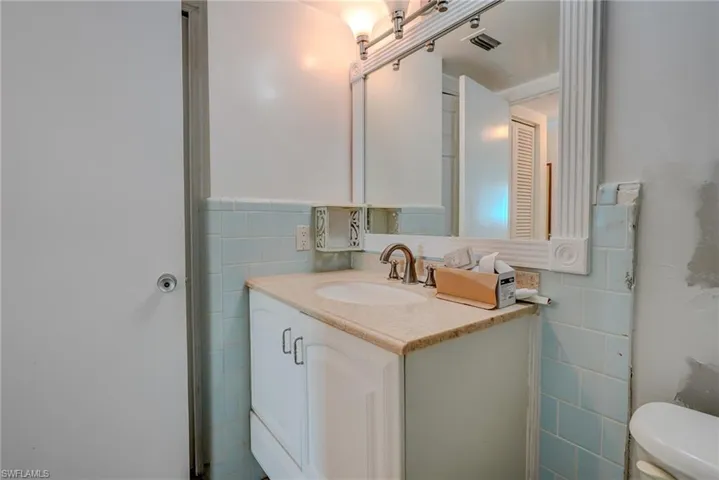 Half bath with tile walls and vanity
