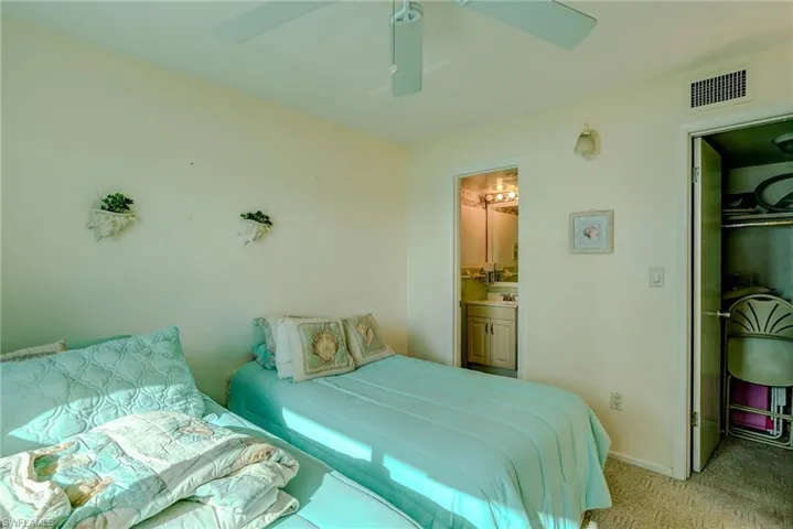 Bedroom with a ceiling fan, ensuite bath, and a spacious closet