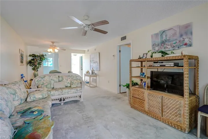 Carpeted living area featuring ceiling fan and baseboards