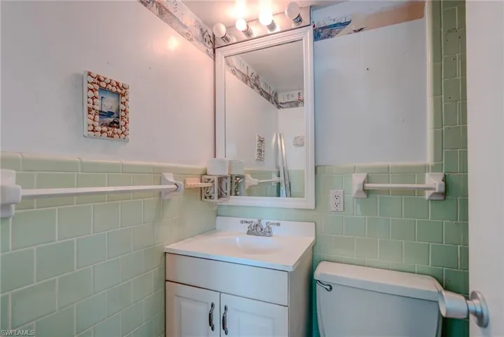 Bathroom with vanity, tile walls, and a wainscoted wall