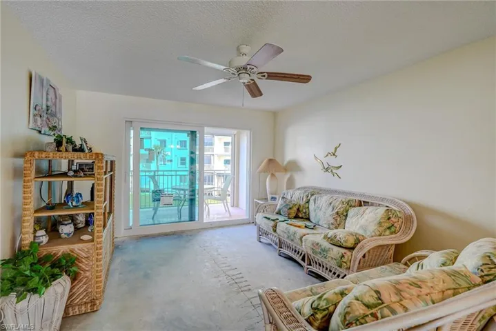 Living area with a textured ceiling, unfinished concrete floors, and ceiling fan