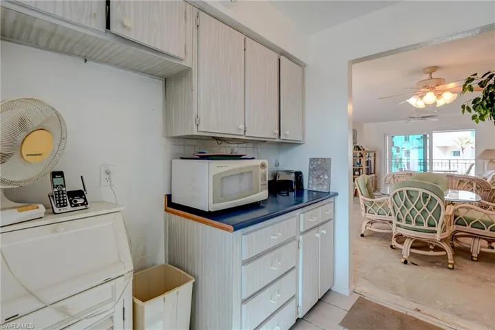 Kitchen with white microwave, tasteful backsplash, a ceiling fan, and light tile patterned floors
