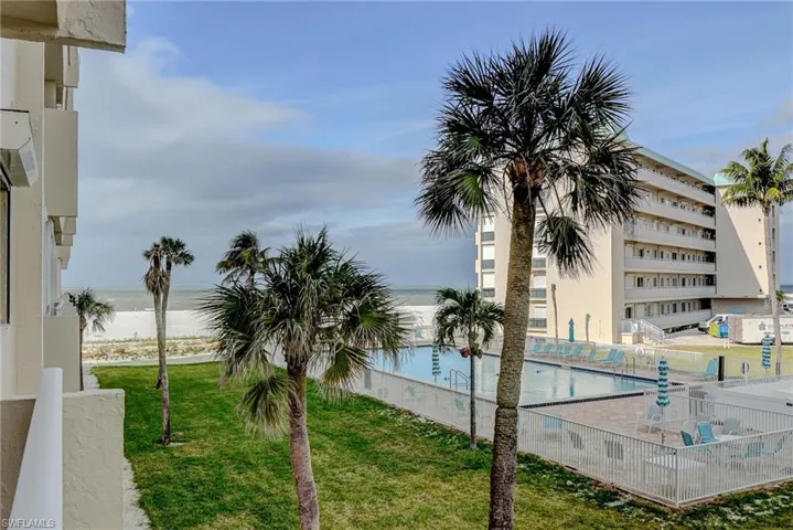 Community pool with view of water and beach and a lawn
