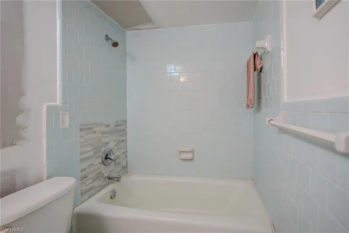 Full bath featuring tub / shower combination and tile walls