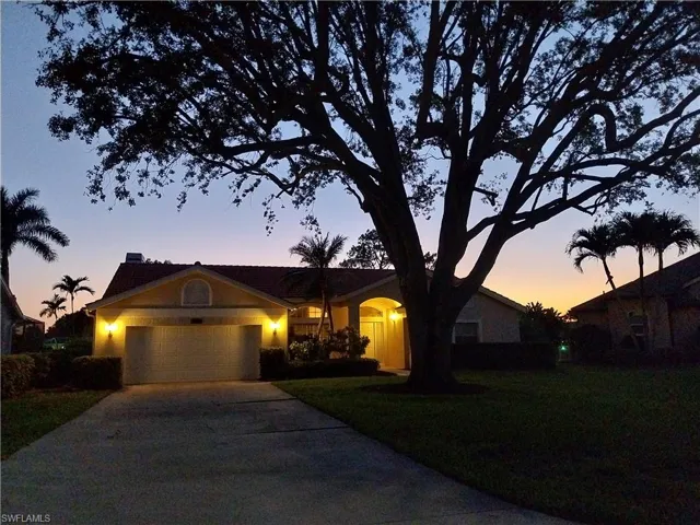 Ranch-style house featuring an attached garage, driveway, a front yard, and stucco siding